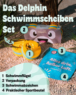 Gelb-türkise Schwimmscheiben mit Flossi-Verpackung, Schwimmabzeichen und türkisem Sportbeutel auf Kies